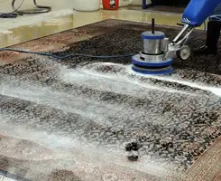 Professional rug cleaning with a rotary floor machine and shampoo foam, deep-cleaning an area rug, in Birmingham, AL.